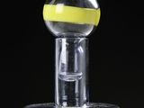 a glass bottle with a yellow cap on top of it