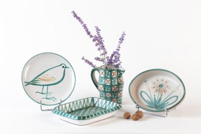 un vase avec des fleurs et une assiette sur laquelle est représenté un oiseau