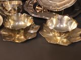 a lot of silver plates and bowls on a table