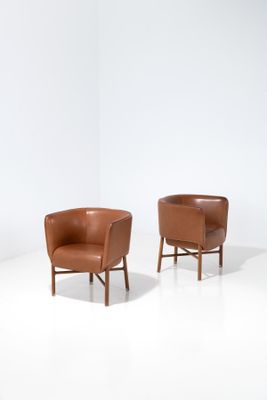 deux fauteuils en cuir marron posés sur un sol blanc