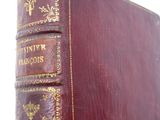 an old book sitting on top of a wooden table next to a white wall