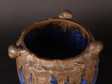 a blue and gold vase sitting on a black surface