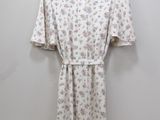 a white floral dress hanging on a hanger against a wall