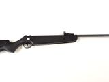 un fusil noir posé sur une surface blanche, avec un fond blanc