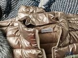 a gold jacket with a fur collar on a bed