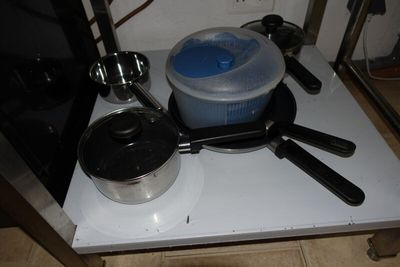 pots and pans sit on a stove top with a microwave in the background