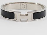 a close up of a black and silver bracelet on a white surface