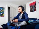 a young boy sitting on a bed playing a video game