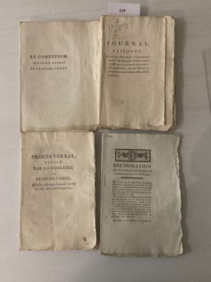 trois vieux livres exposés sur une table, accompagnés d'une étiquette en papier