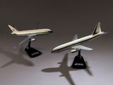 Trois maquettes d'avions sont posées sur un socle, sur une surface grise.