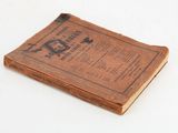 an old book sitting on top of a table on a white surface