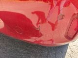 a close up of a red car that has been dented