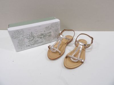 Les sandales dorées se trouvent à côté de la boîte à chaussures.