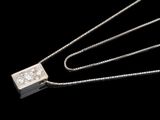 un gros plan d'un pendentif en diamant suspendu à une chaîne, sur fond noir
