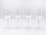 quatre verres à vin vides alignés en rang sur une surface blanche