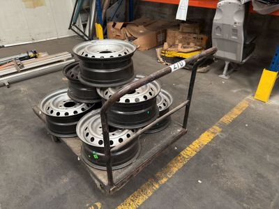 four rims on a cart in a garage