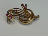 une broche en or ornée de pierres roses et bleues
