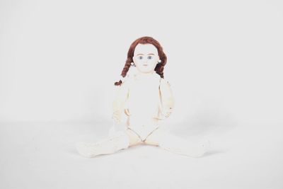 an image of a doll sitting on the ground with a white background
