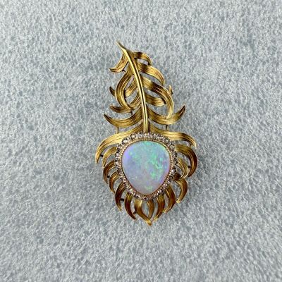 une broche en oplite et diamants posée sur un tissu blanc