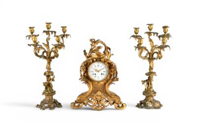 trois bougeoirs dorés et une horloge sur fond blanc