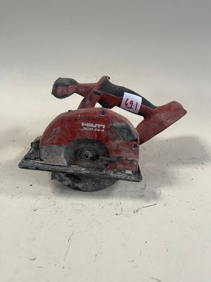 une scie circulaire rouge posée sur une surface blanche
