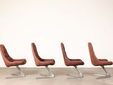 three brown leather chairs sitting in a row on a concrete floor