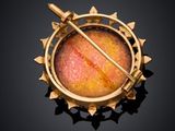 an image of a gold broochle with a stick in it