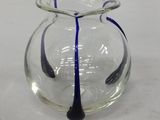 un vase en verre avec une anse bleue posé sur une table