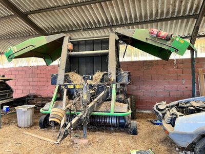 un tracteur garé dans une grange où il y a du foin par terre