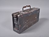 une vieille valise avec une poignée, posée sur une surface blanche