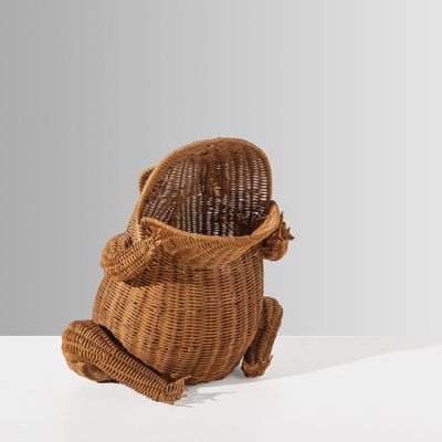 un petit panier en osier muni d'une anse, posé sur une surface blanche