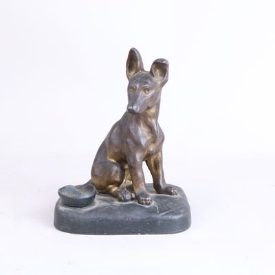 statue en bronze représentant un chien assis sur un rocher, sur fond blanc