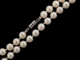 a close up of two strands of white pearls on a black background