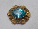 une image représentant une broche ornée d'une pierre bleue entourée de fleurs