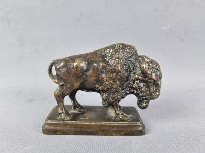 statue en bronze représentant un bison sur un socle, sur fond blanc