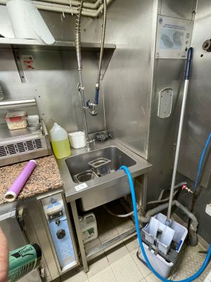 a man standing in a kitchen with a bucket and a hose