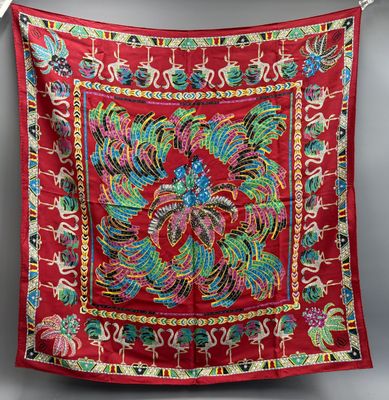 a red cloth with colorful designs hanging on a clothes line