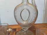 a glass vase sitting on a table next to two cups