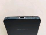 the back of a black samsung phone sitting on top of a white table