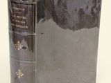 un vieux livre à la couverture noire posé sur une table blanche