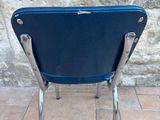 a blue chair that is sitting in front of a stone wall