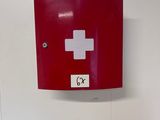 a red box with a white cross on it on the wall
