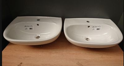 two white sinks sitting on top of a wooden shelf