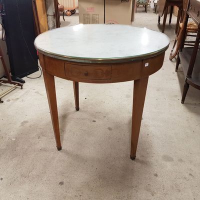 une table ronde avec un plateau en verre au milieu d'une pièce