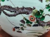 a white vase with flowers on it sitting on a table