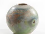 a green and brown vase sitting on a white surface