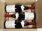 three bottles of wine in a cardboard box on a table