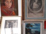 many framed pictures on the floor next to a red wall