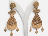 une paire de boucles d'oreilles en or ornées de pompons, posée sur un présentoir blanc