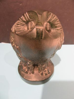 un vase en bronze exposé sur une table blanche